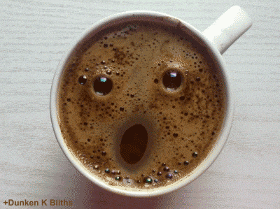 Gif of a cup of coffee seen from the top. The bubbles in the coffee look like a face that gives a wink
