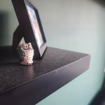 Dust on a wall shelf with a photo and an owl decoration. displaying the need of an air purifier for the nursery