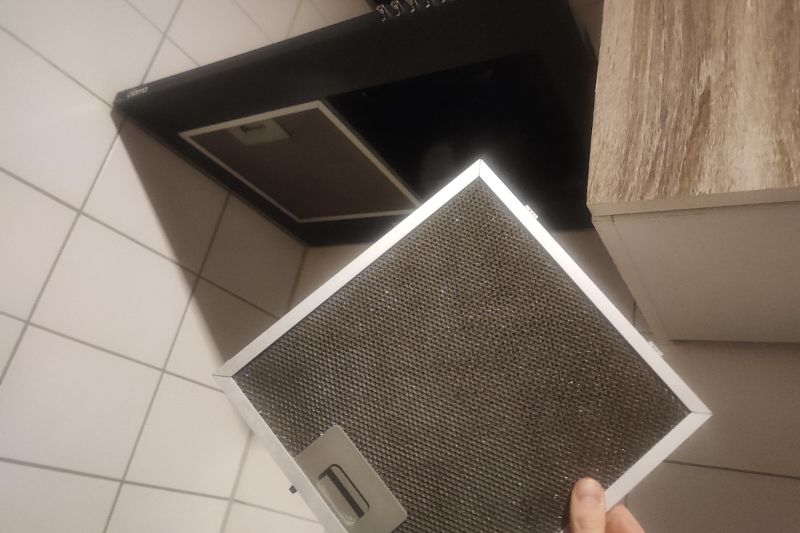 How to Clean a Range Hood Filter (Degrease in Minutes) Clean range hood filter being placed back into the range hood after cleaning