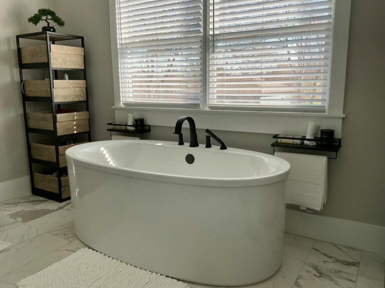 How to Unclog a Bathtub Drain (5 Simple Methods) A large white bathtub positioned in a modern bathroom setting.