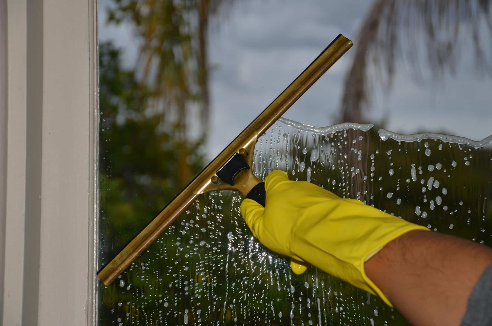 How to Remove Water Stains from Glass (Easy Methods) Squeegee being used to remove water droplets from a glass surface to prevent mineral stains